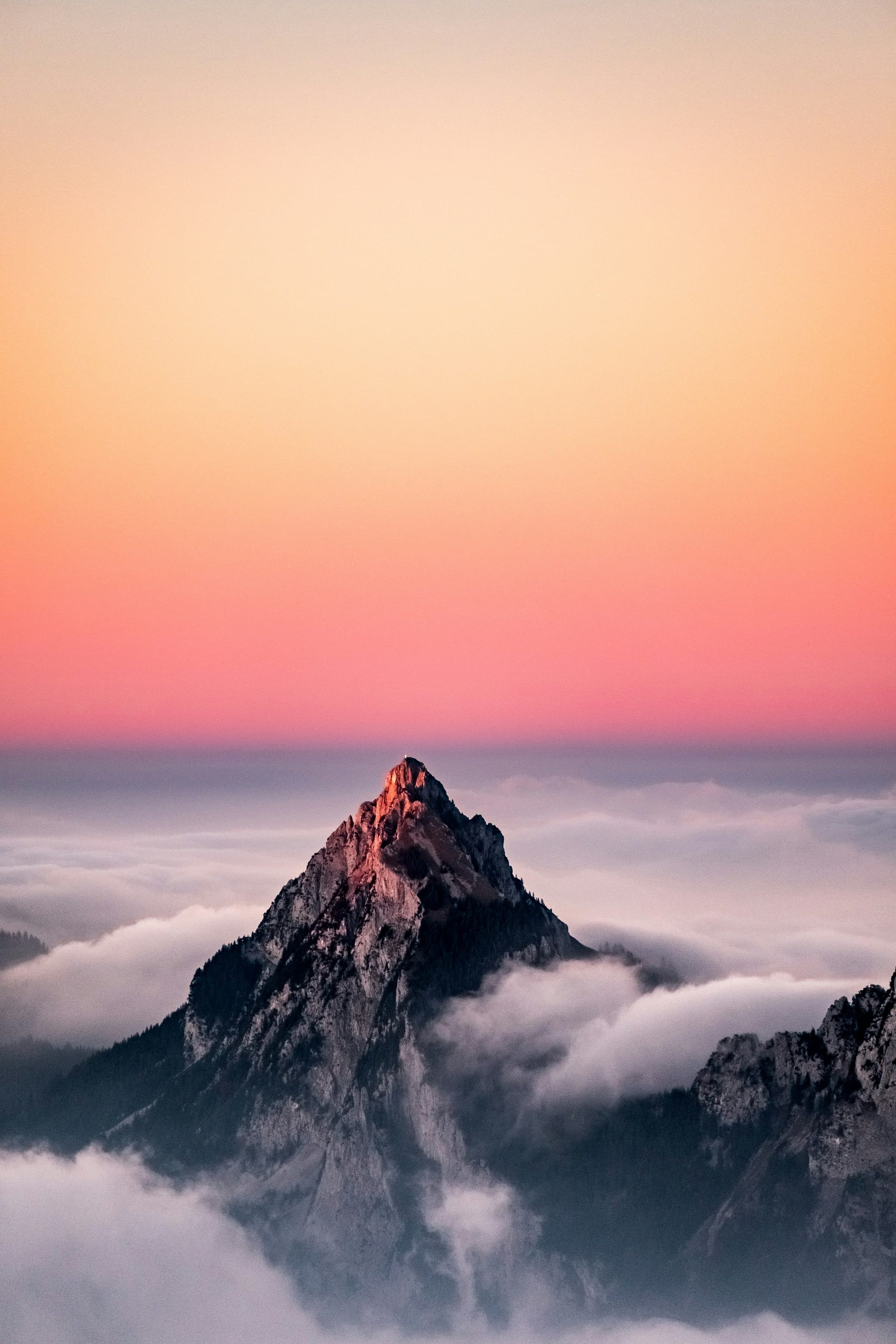 An alpine summit emerging from a sea of fog at sunset